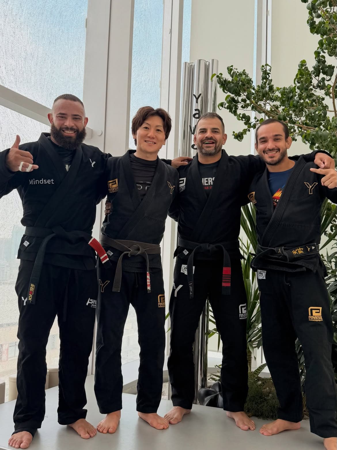 Uriel Meneses ao lado de três praticantes de jiu-jitsu em uma academia de Tóquio